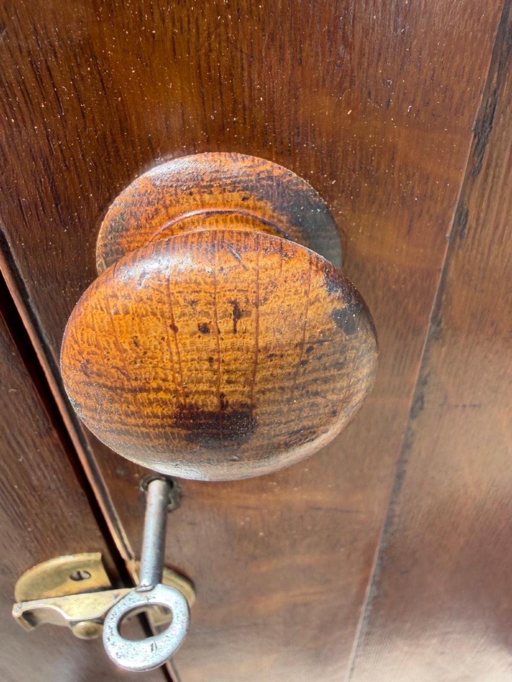 A tall Victorian oak two-door cupboard featuring recessed panel doors, turned wooden knobs, brass latches, and turned bun feet. View IV