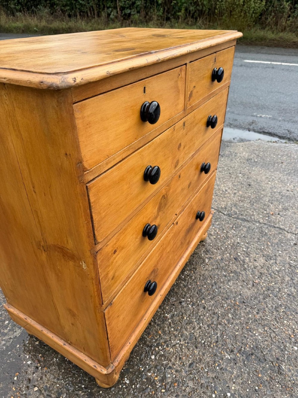 A Victorian pine chest of drawers featuring two small drawers above three graduated long drawers, detailed with dark turned knobs and resting on turned bun feet. View IV