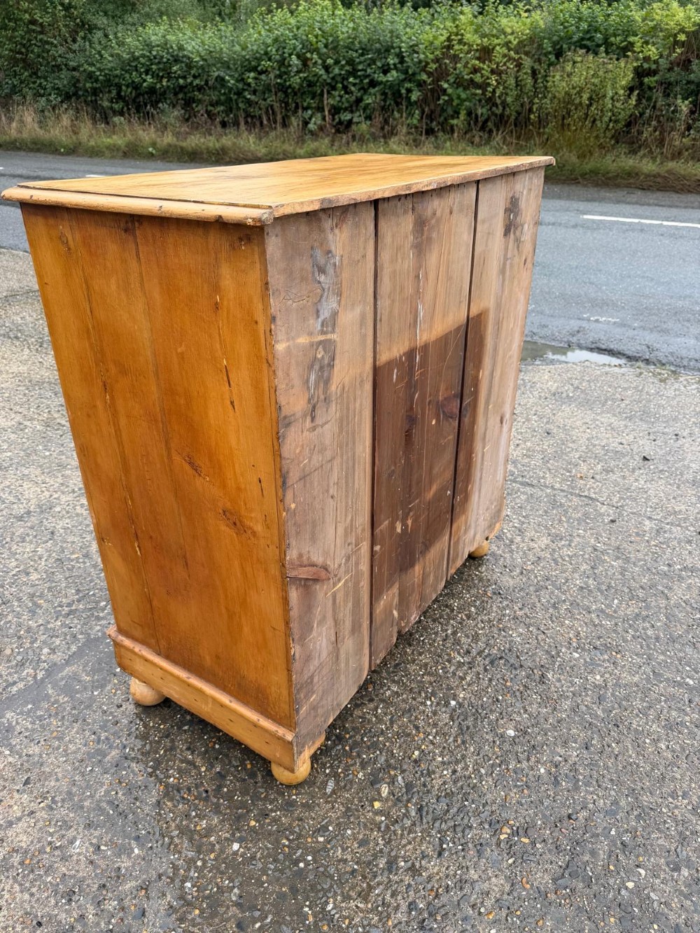A Victorian pine chest of drawers featuring two small drawers above three graduated long drawers, detailed with dark turned knobs and resting on turned bun feet. View V