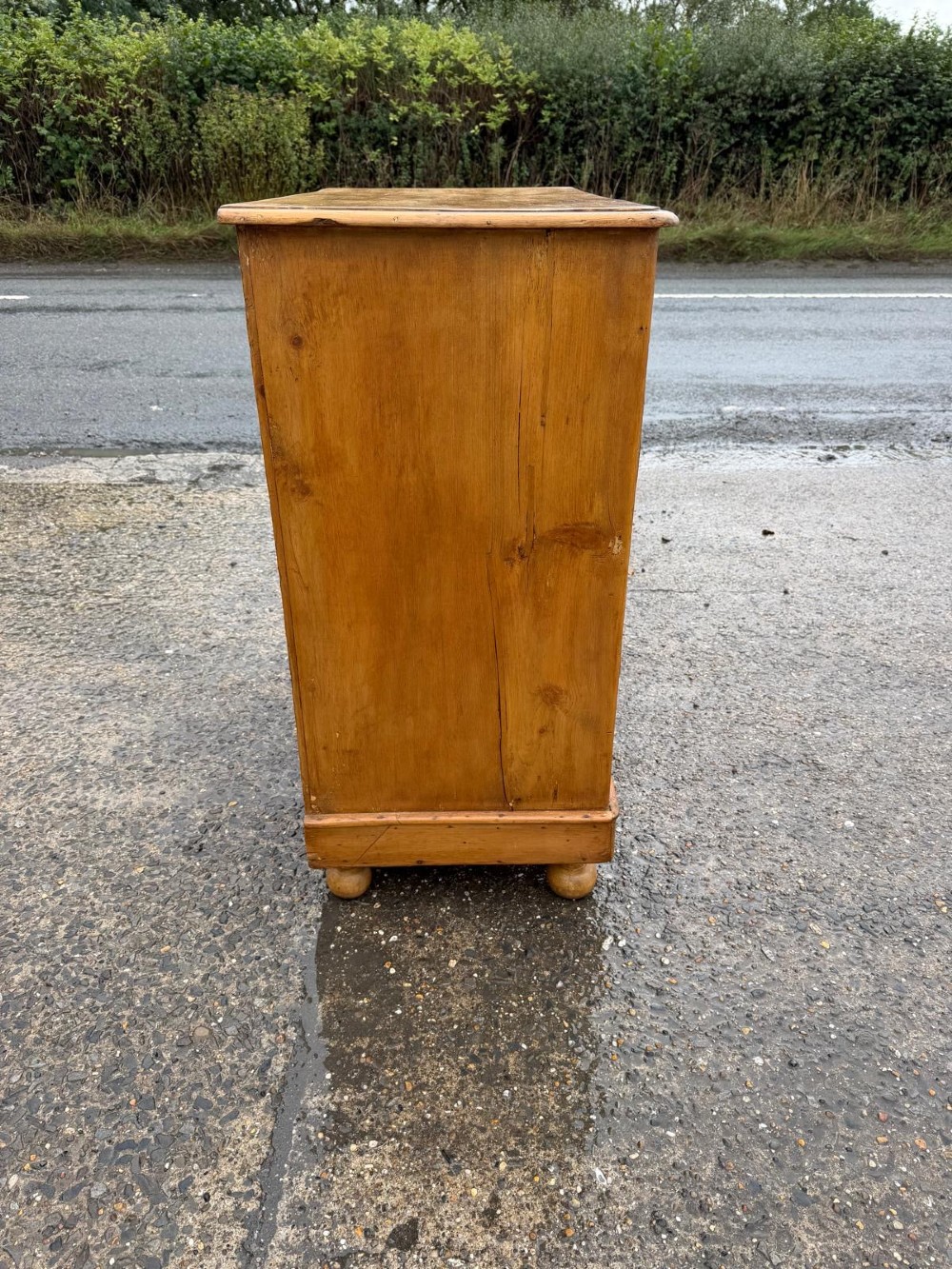 A Victorian pine chest of drawers featuring two small drawers above three graduated long drawers, detailed with dark turned knobs and resting on turned bun feet. View VI