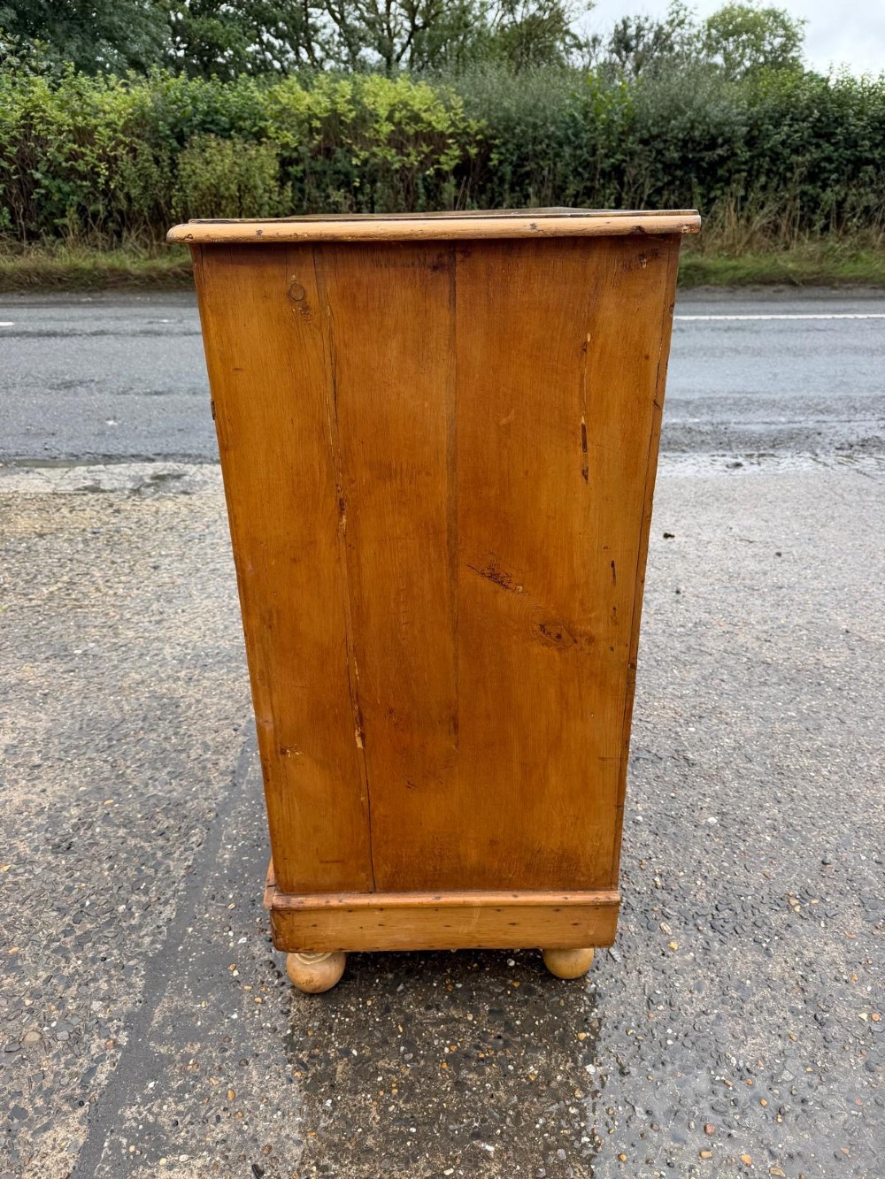 A Victorian pine chest of drawers featuring two small drawers above three graduated long drawers, detailed with dark turned knobs and resting on turned bun feet. View VII