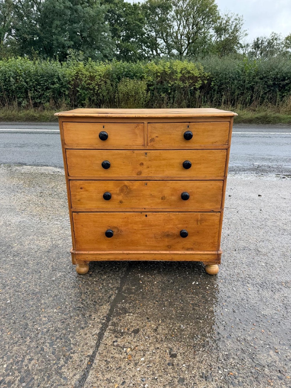 A Victorian pine chest of drawers featuring two small drawers above three graduated long drawers, detailed with dark turned knobs and resting on turned bun feet. View IX
