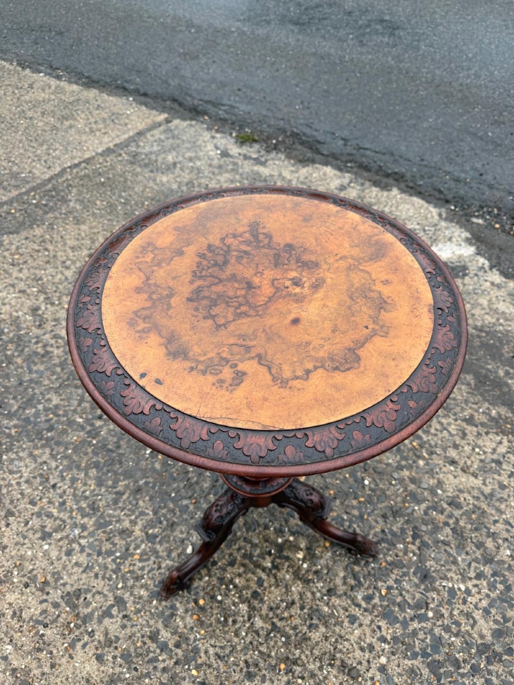A Victorian mahogany tripod side table with a circular top containing a burr wood inset, a carved border, a turned central support, and three carved splayed legs. View II