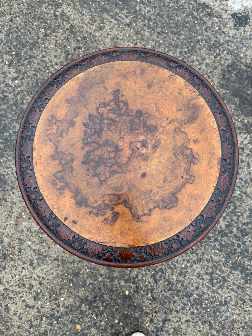 A Victorian mahogany tripod side table with a circular top containing a burr wood inset, a carved border, a turned central support, and three carved splayed legs. View IV