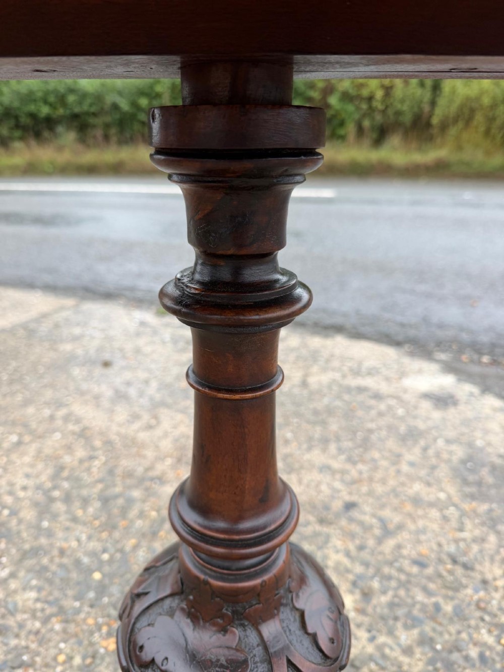 A Victorian mahogany tripod side table with a circular top containing a burr wood inset, a carved border, a turned central support, and three carved splayed legs. View V
