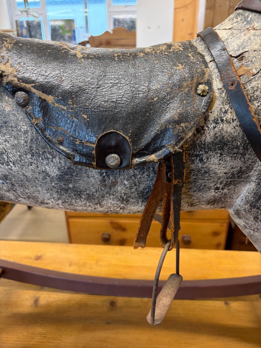 A 19th-century carved wooden primitive rocking horse with weathered paint, leather tack, and dark reddish-brown bow rockers. View II