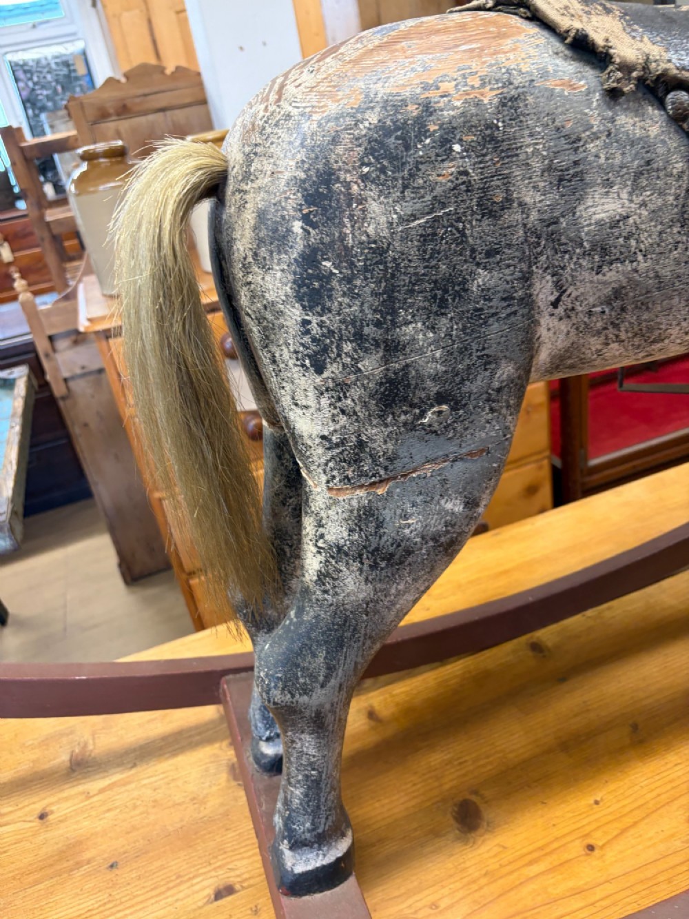 A 19th-century carved wooden primitive rocking horse with weathered paint, leather tack, and dark reddish-brown bow rockers. View III