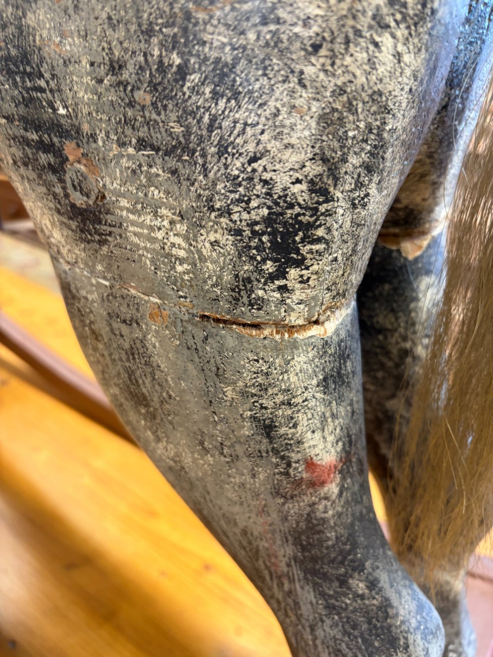 A 19th-century carved wooden primitive rocking horse with weathered paint, leather tack, and dark reddish-brown bow rockers. View IV