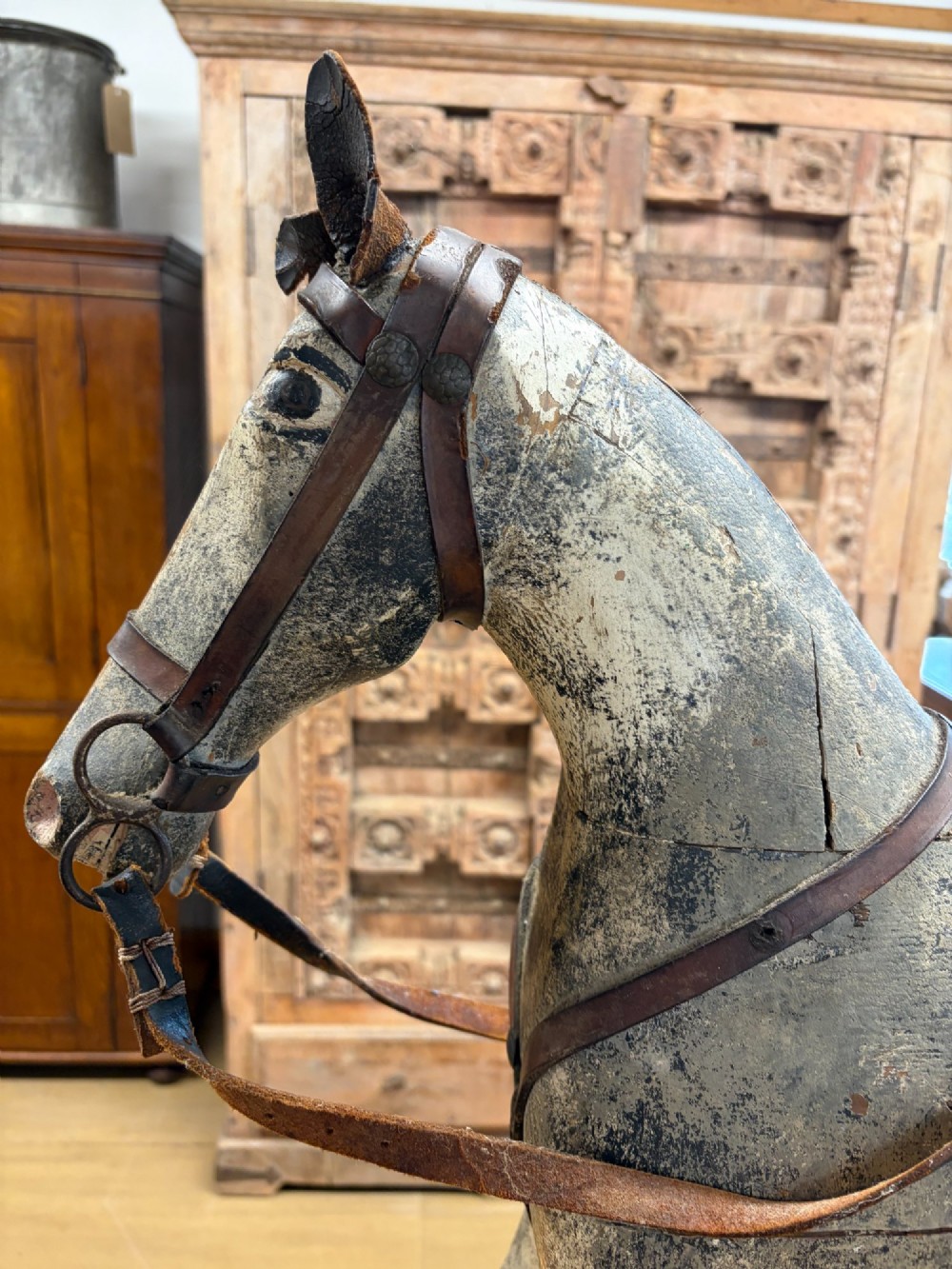 A 19th-century carved wooden primitive rocking horse with weathered paint, leather tack, and dark reddish-brown bow rockers. View VI