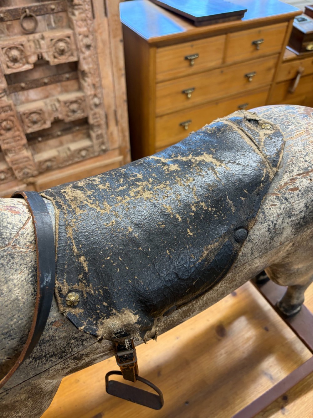 A 19th-century carved wooden primitive rocking horse with weathered paint, leather tack, and dark reddish-brown bow rockers. View VII