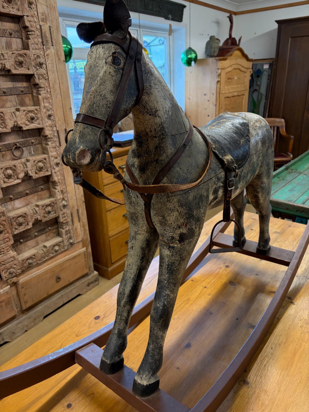 A 19th-century carved wooden primitive rocking horse with weathered paint, leather tack, and dark reddish-brown bow rockers. View IX
