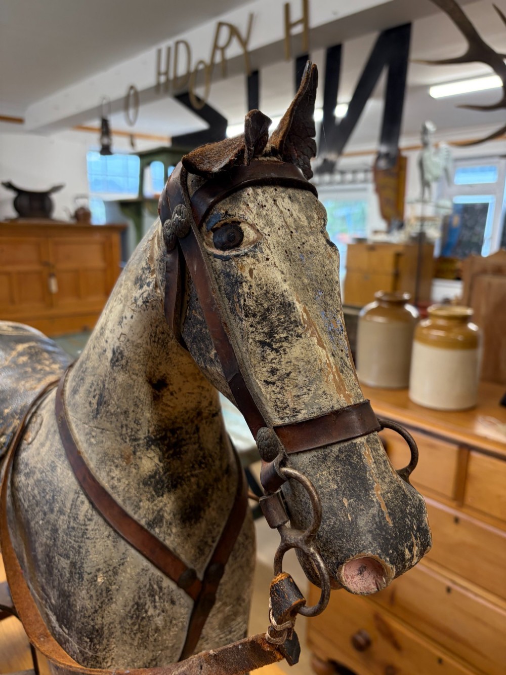 A 19th-century carved wooden primitive rocking horse with weathered paint, leather tack, and dark reddish-brown bow rockers. View XI