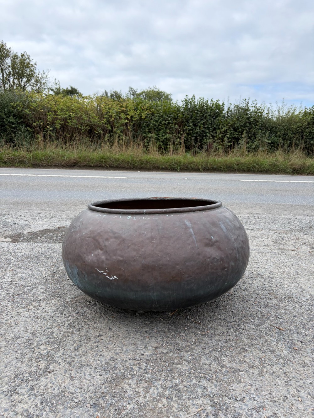 A large 19th-century rounded copper pot with a hand-hammered surface, rolled rim, and dark patinated finish.