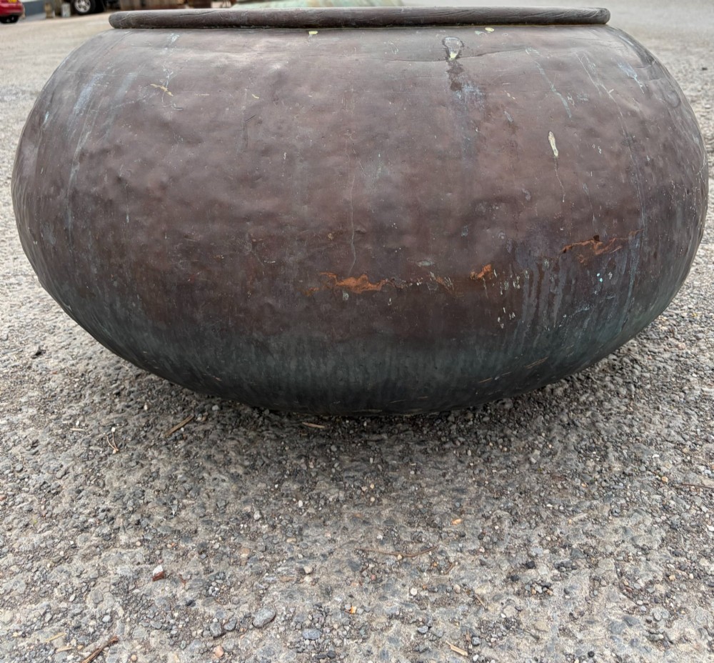 A large 19th-century rounded copper pot with a hand-hammered surface, rolled rim, and dark patinated finish. View II