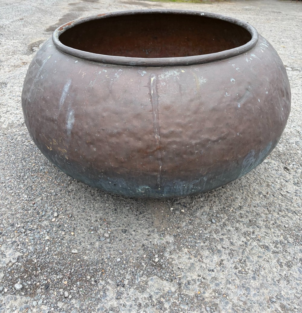 A large 19th-century rounded copper pot with a hand-hammered surface, rolled rim, and dark patinated finish. View V