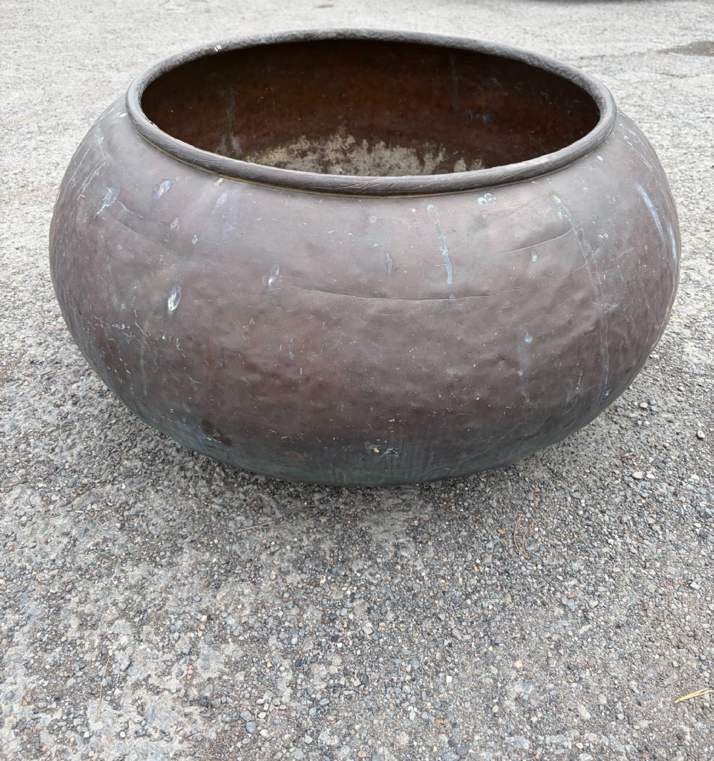 A large 19th-century rounded copper pot with a hand-hammered surface, rolled rim, and dark patinated finish. View VI