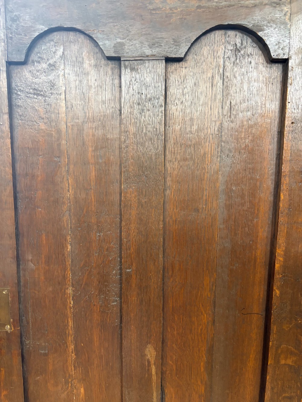An antique George III oak housekeepers cupboard with arched fielded panels on the top doors above a base of drawers with brass handles. View V