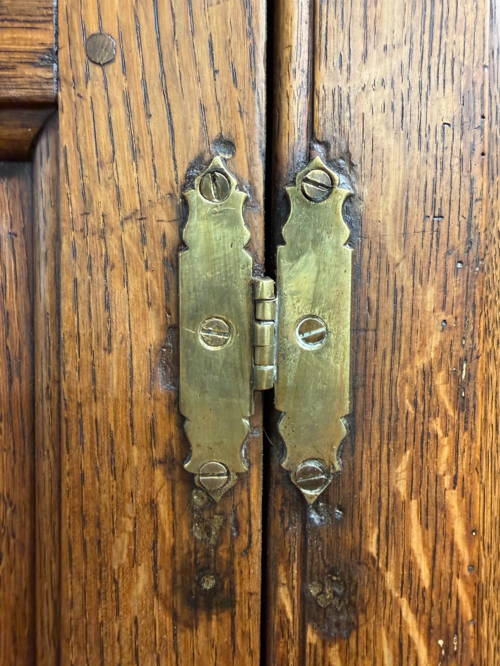 An antique George III oak housekeepers cupboard with arched fielded panels on the top doors above a base of drawers with brass handles. View IX