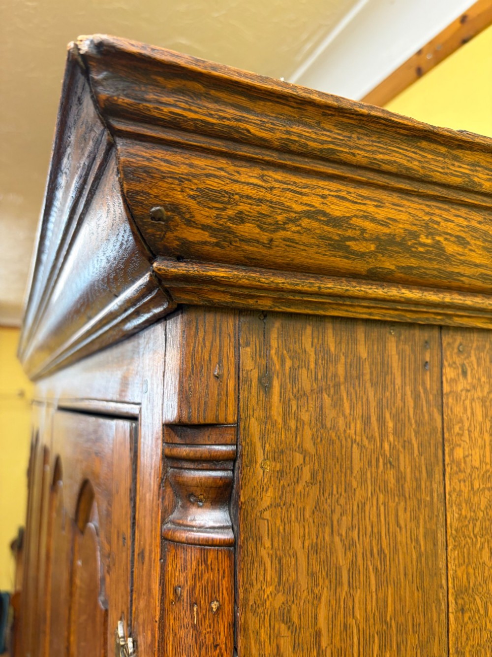 An antique George III oak housekeepers cupboard with arched fielded panels on the top doors above a base of drawers with brass handles. View X