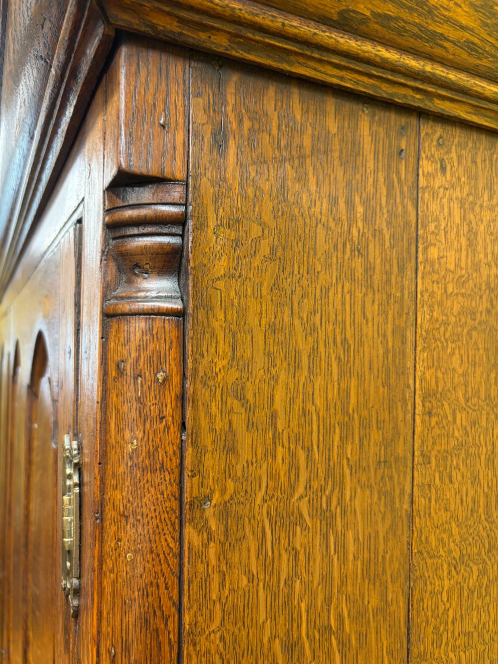 An antique George III oak housekeepers cupboard with arched fielded panels on the top doors above a base of drawers with brass handles. View XI