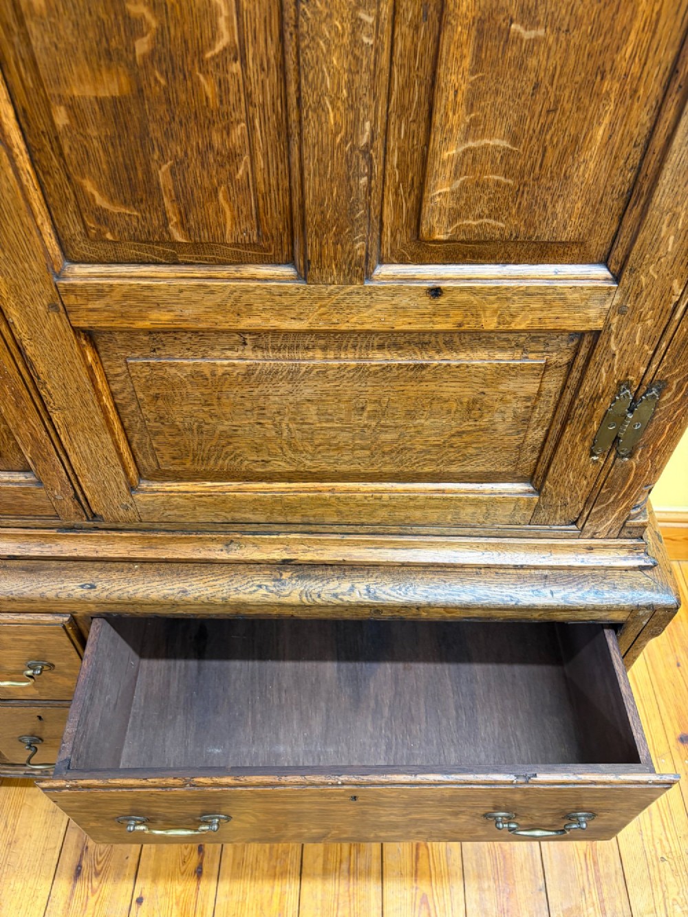 An antique George III oak housekeepers cupboard with arched fielded panels on the top doors above a base of drawers with brass handles. View XII