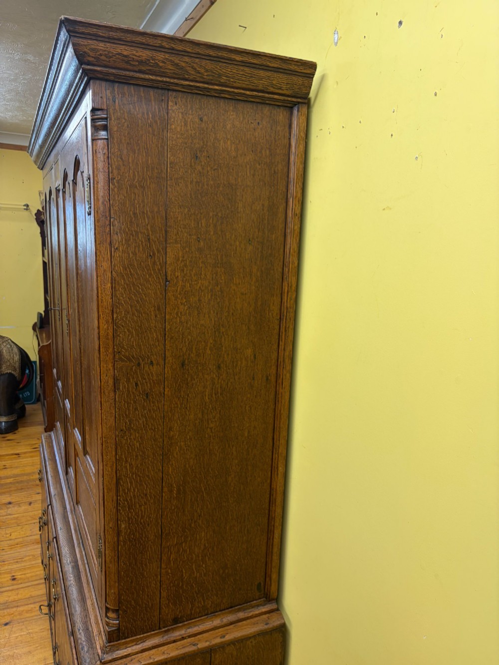 An antique George III oak housekeepers cupboard with arched fielded panels on the top doors above a base of drawers with brass handles. View XV