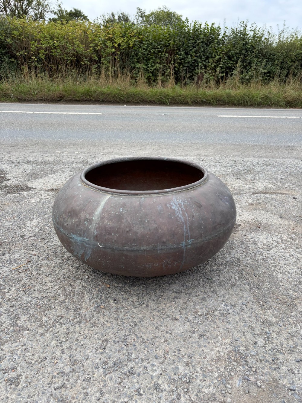 A large bulbous 19th century copper pot featuring a rolled rim, a horizontal seam line, and natural verdigris oxidisation across its surface.