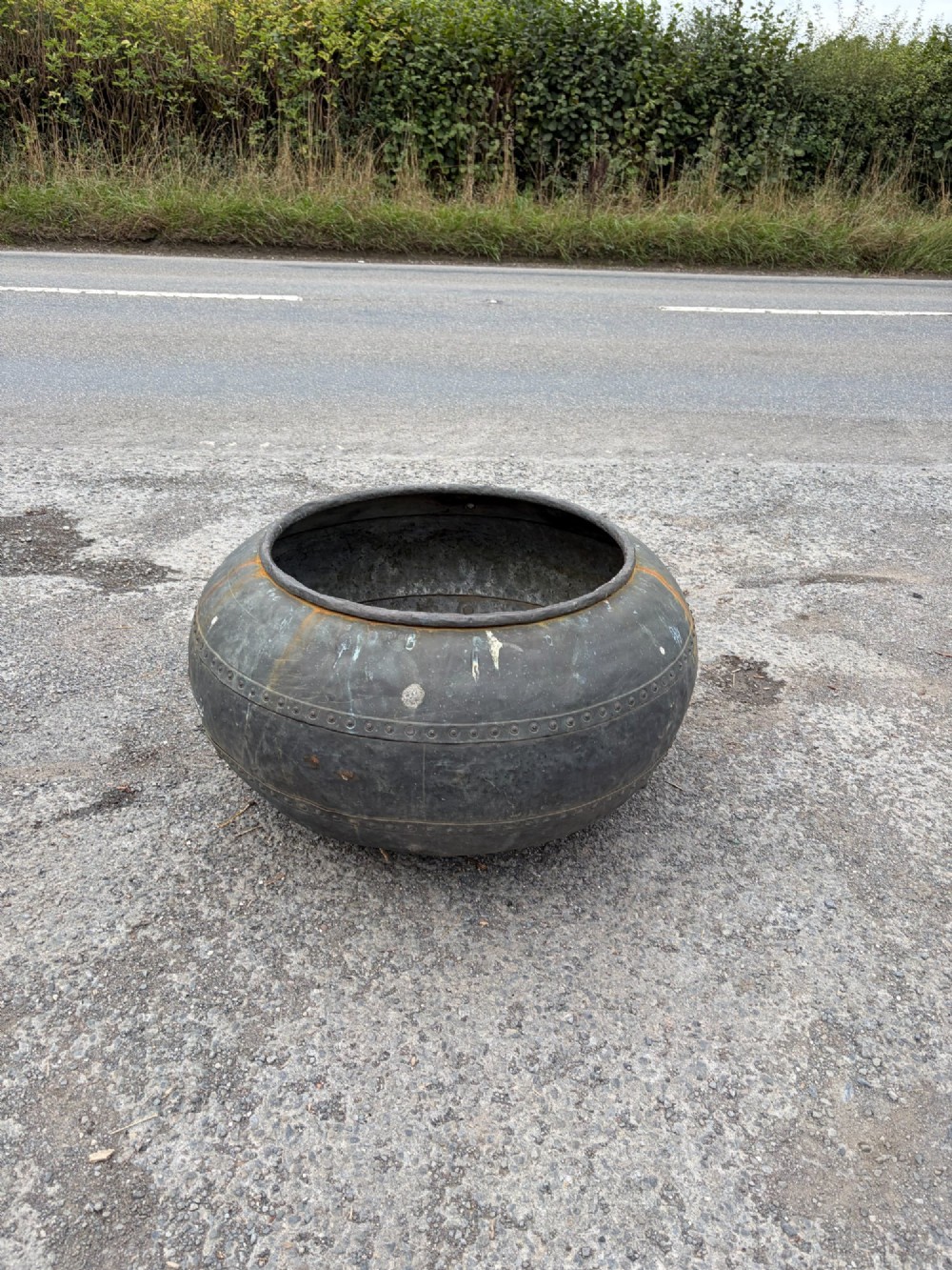 A large bulbous nineteenth-century copper vessel featuring a dark aged patina, riveted band detail, and wide circular opening.