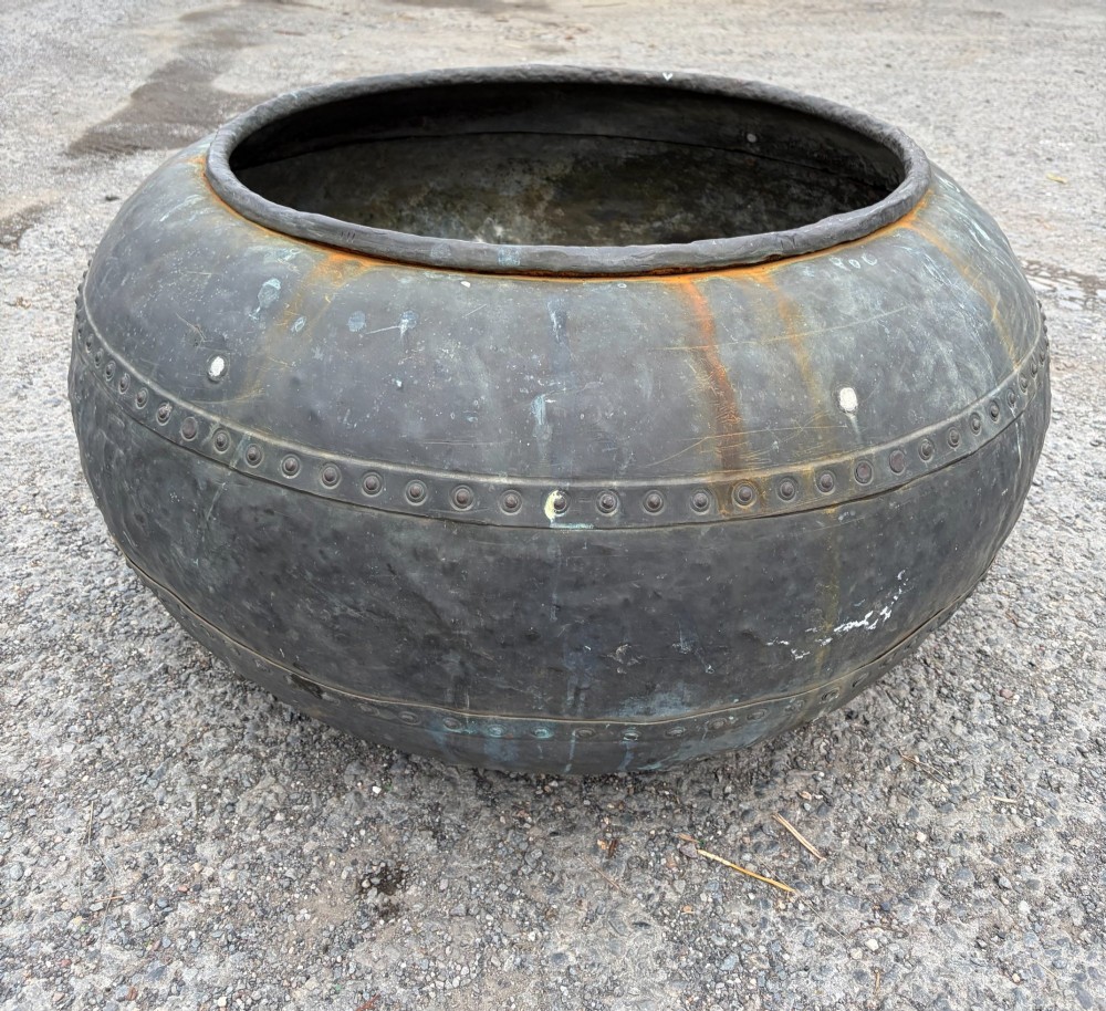 A large bulbous nineteenth-century copper vessel featuring a dark aged patina, riveted band detail, and wide circular opening. View V
