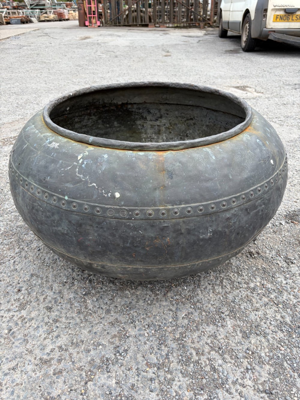 A large bulbous nineteenth-century copper vessel featuring a dark aged patina, riveted band detail, and wide circular opening. View VI