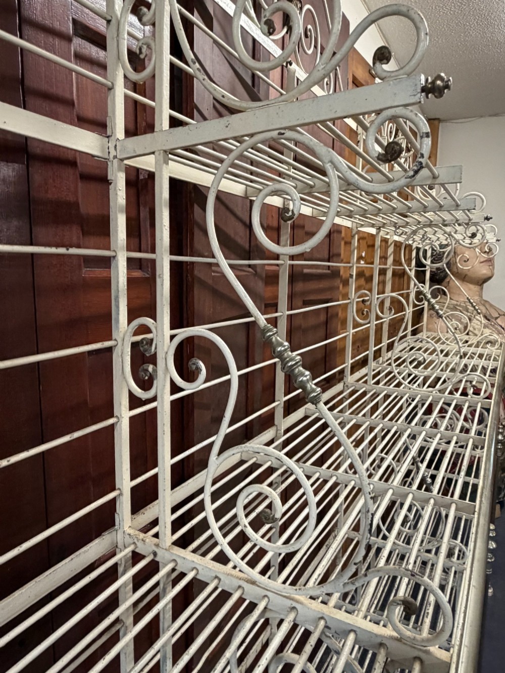 A large, multi-tiered French wrought iron bakers rack painted cream, decorated with scrollwork cresting and brass decorative elements. View IV