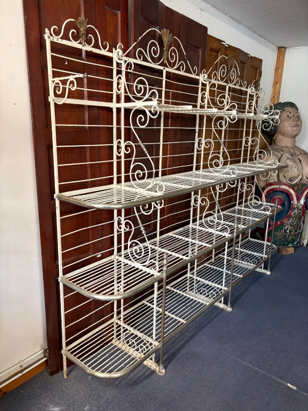 A large, multi-tiered French wrought iron bakers rack painted cream, decorated with scrollwork cresting and brass decorative elements. View V