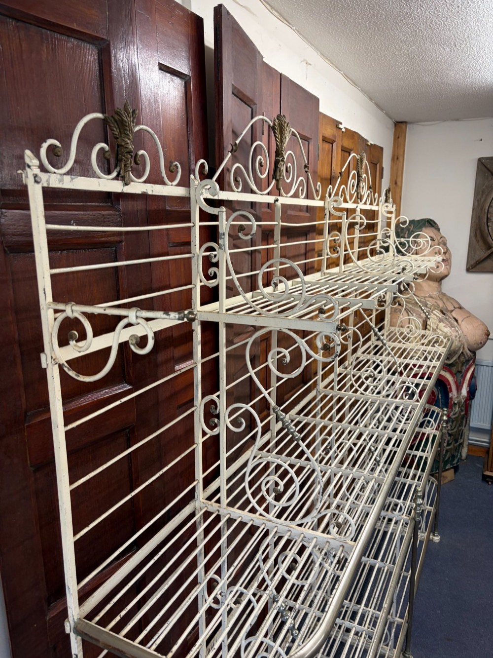 A large, multi-tiered French wrought iron bakers rack painted cream, decorated with scrollwork cresting and brass decorative elements. View IX