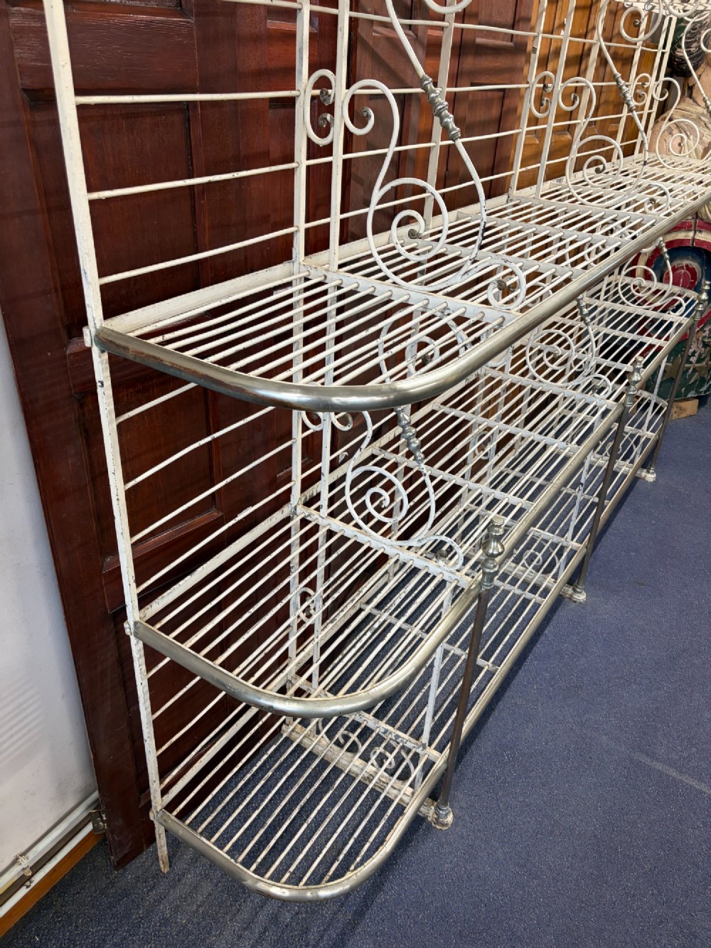 A large, multi-tiered French wrought iron bakers rack painted cream, decorated with scrollwork cresting and brass decorative elements. View X