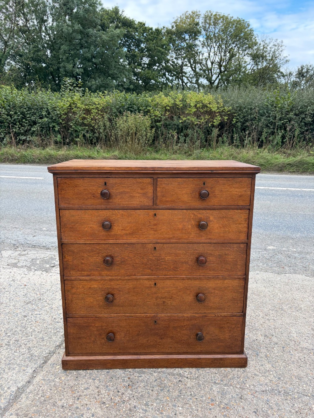 A Victorian warm brown oak chest of drawers featuring two short drawers above four full-width long drawers with turned wooden handles and keyholes.
