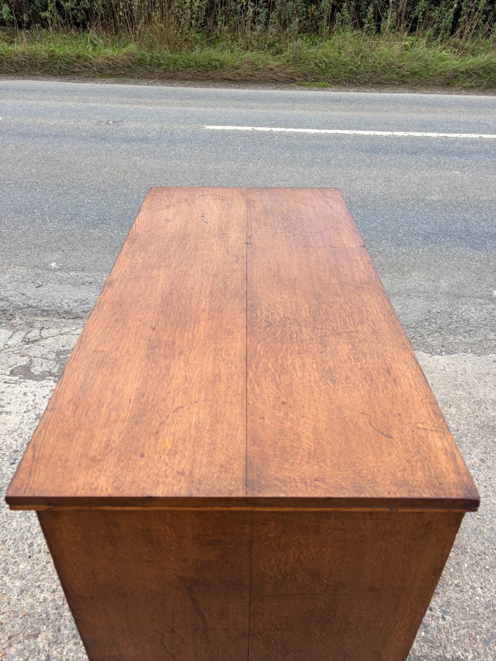 A Victorian warm brown oak chest of drawers featuring two short drawers above four full-width long drawers with turned wooden handles and keyholes. View V