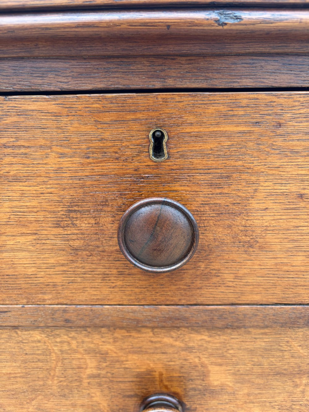 A Victorian warm brown oak chest of drawers featuring two short drawers above four full-width long drawers with turned wooden handles and keyholes. View VIII