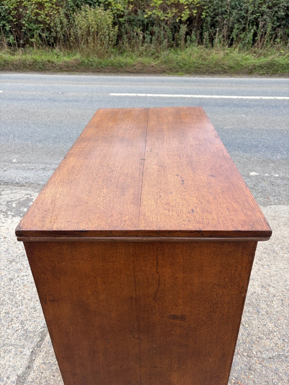 A Victorian warm brown oak chest of drawers featuring two short drawers above four full-width long drawers with turned wooden handles and keyholes. View X