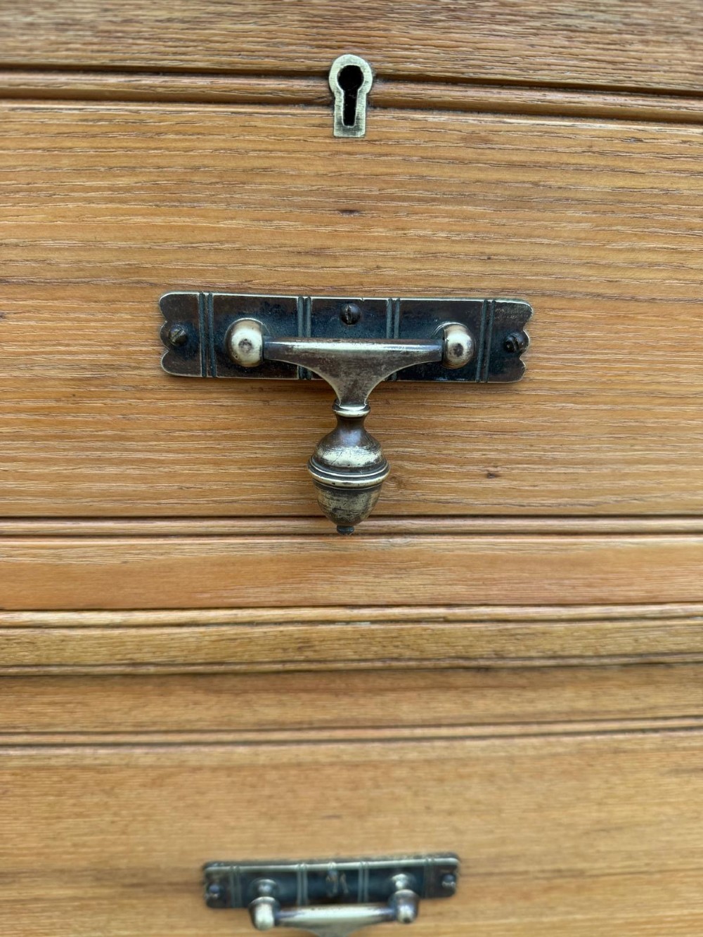 A solid oak chest of drawers featuring a two over three drawer layout with fluted side pilasters and brass acorn drop handles set on a solid base. View V