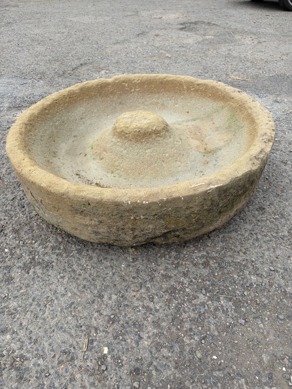 A circular hand-carved antique sandstone pig trough featuring a raised central cone and weathered exterior surface. View III