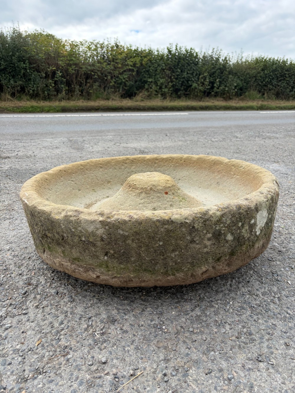 A circular hand-carved antique sandstone pig trough featuring a raised central cone and weathered exterior surface. View IV