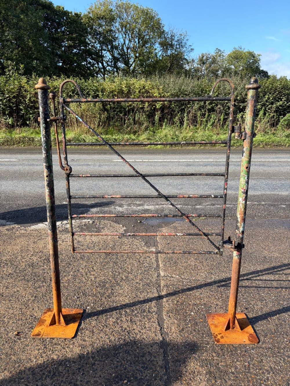 An early 19th-century wrought iron pedestrian field gate with supporting posts, horizontal bars, diagonal bracing, and a weathered paint finish. View II