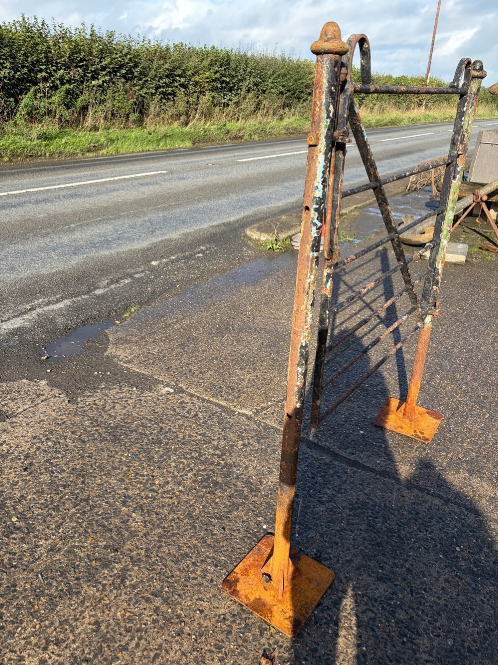 An early 19th-century wrought iron pedestrian field gate with supporting posts, horizontal bars, diagonal bracing, and a weathered paint finish. View V