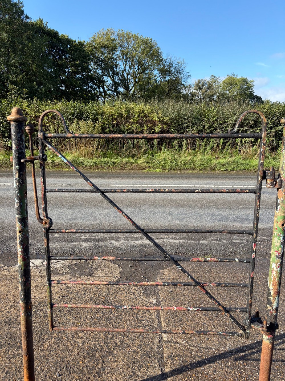 An early 19th-century wrought iron pedestrian field gate with supporting posts, horizontal bars, diagonal bracing, and a weathered paint finish. View VI
