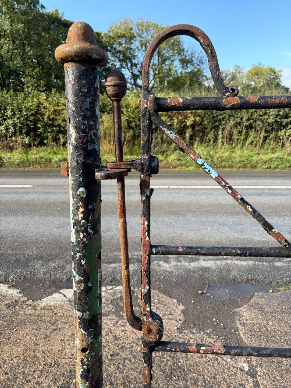 An early 19th-century wrought iron pedestrian field gate with supporting posts, horizontal bars, diagonal bracing, and a weathered paint finish. View X