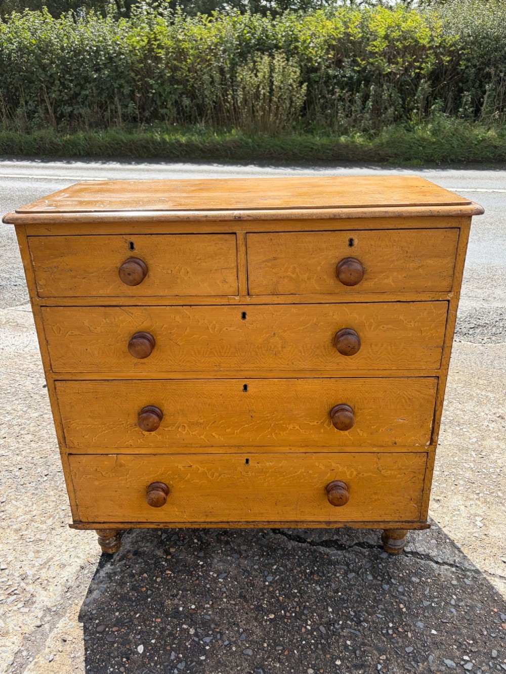 A Victorian pine chest of drawers featuring a faux-grained finish, two short drawers over three long drawers, turned wooden knobs, and turned feet. View II