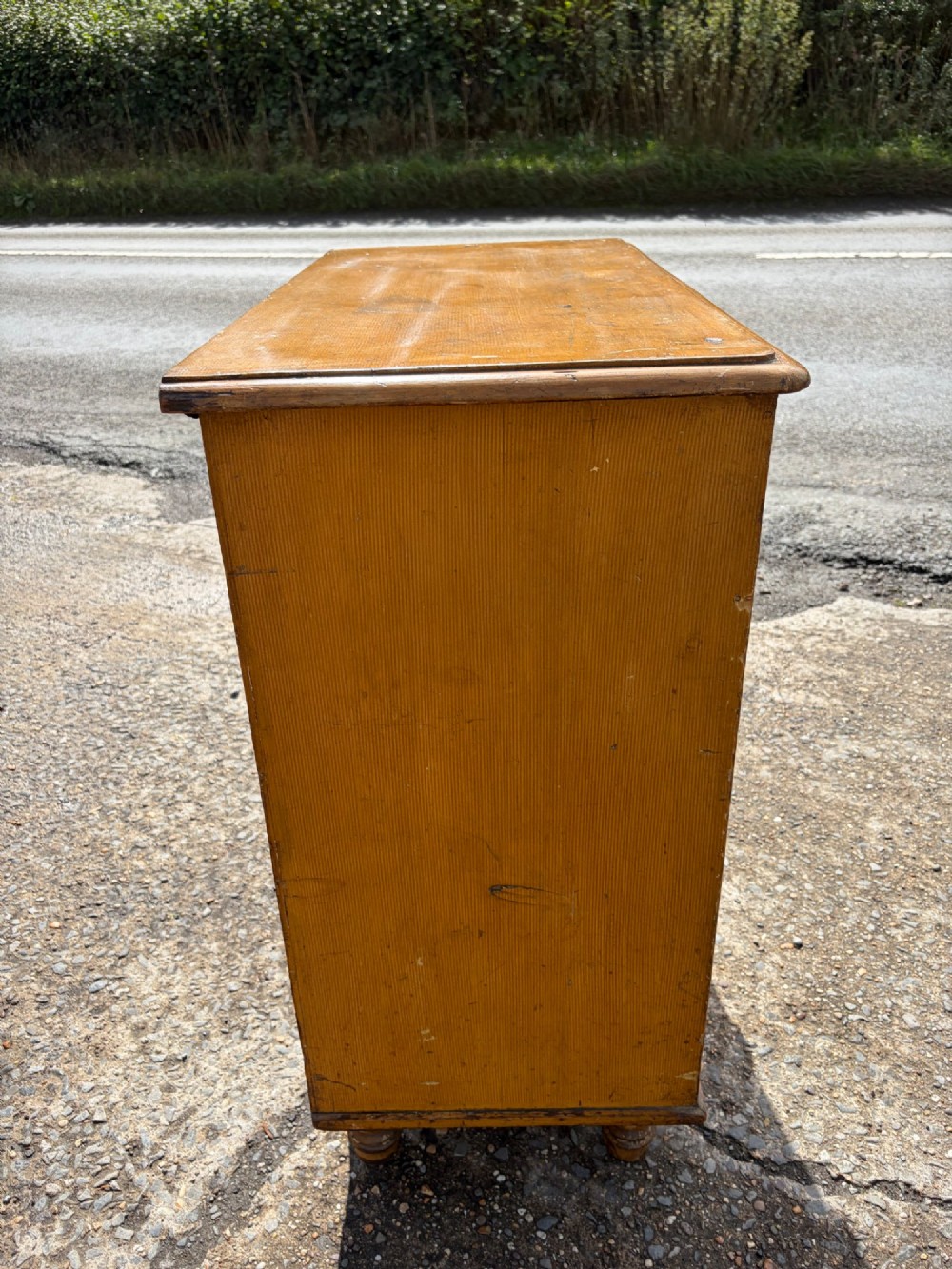 A Victorian pine chest of drawers featuring a faux-grained finish, two short drawers over three long drawers, turned wooden knobs, and turned feet. View VI