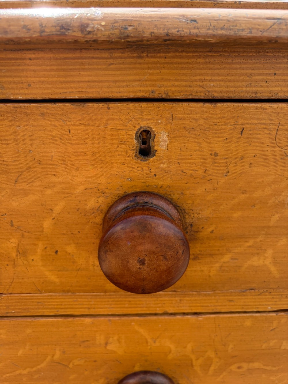 A Victorian pine chest of drawers featuring a faux-grained finish, two short drawers over three long drawers, turned wooden knobs, and turned feet. View X