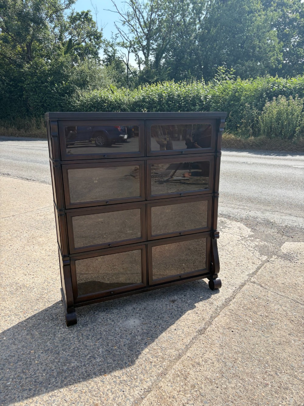 A 1920s dark mahogany double-width sectional bookcase featuring four stacked tiers fitted with glazed up-and-over doors.