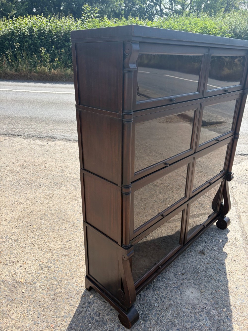 A 1920s dark mahogany double-width sectional bookcase featuring four stacked tiers fitted with glazed up-and-over doors. View V
